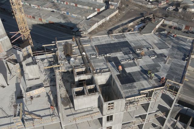 Aerial view of a concrete building under construction beside a tower crane.